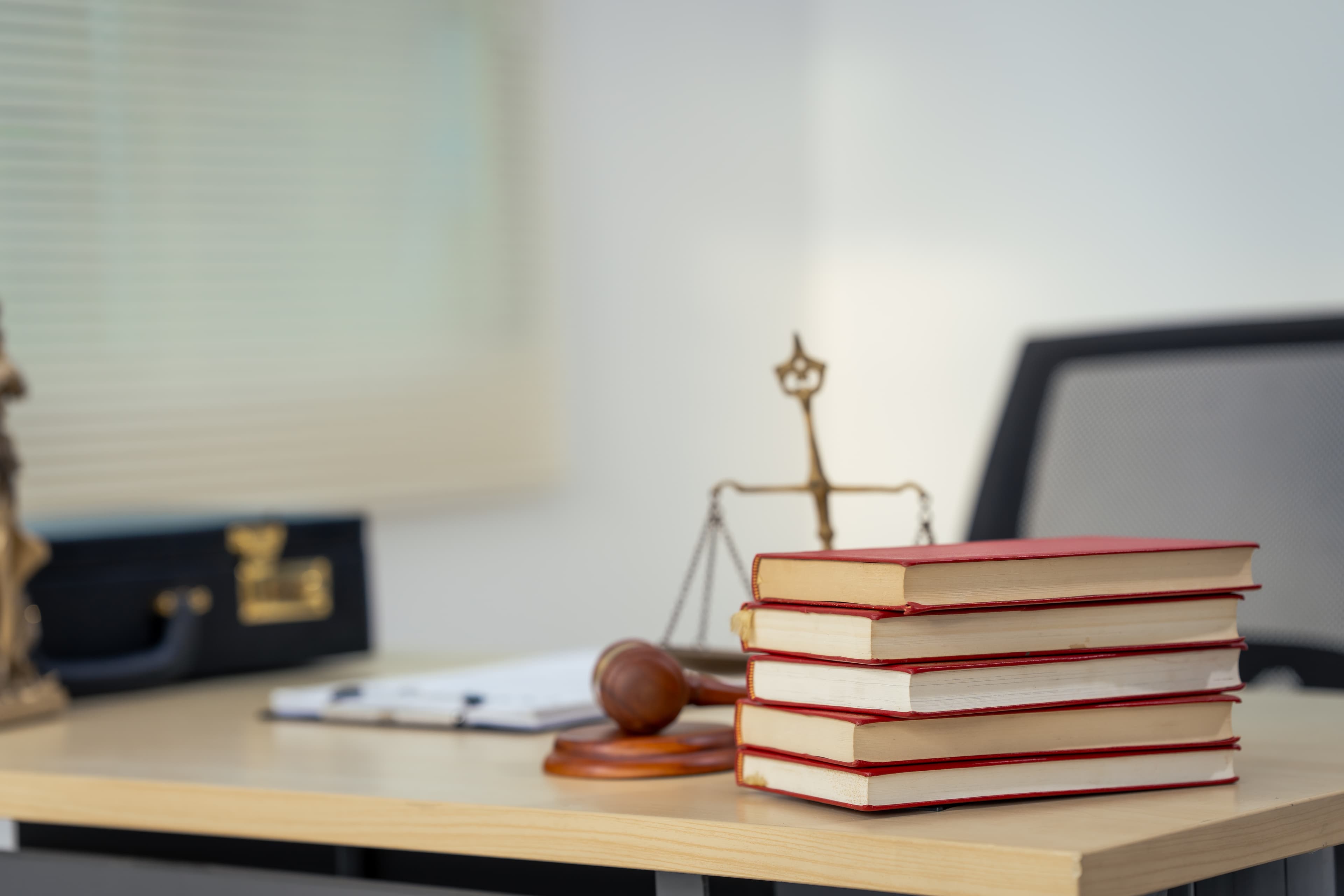 Scales of justice on a wooden desk next to legal books