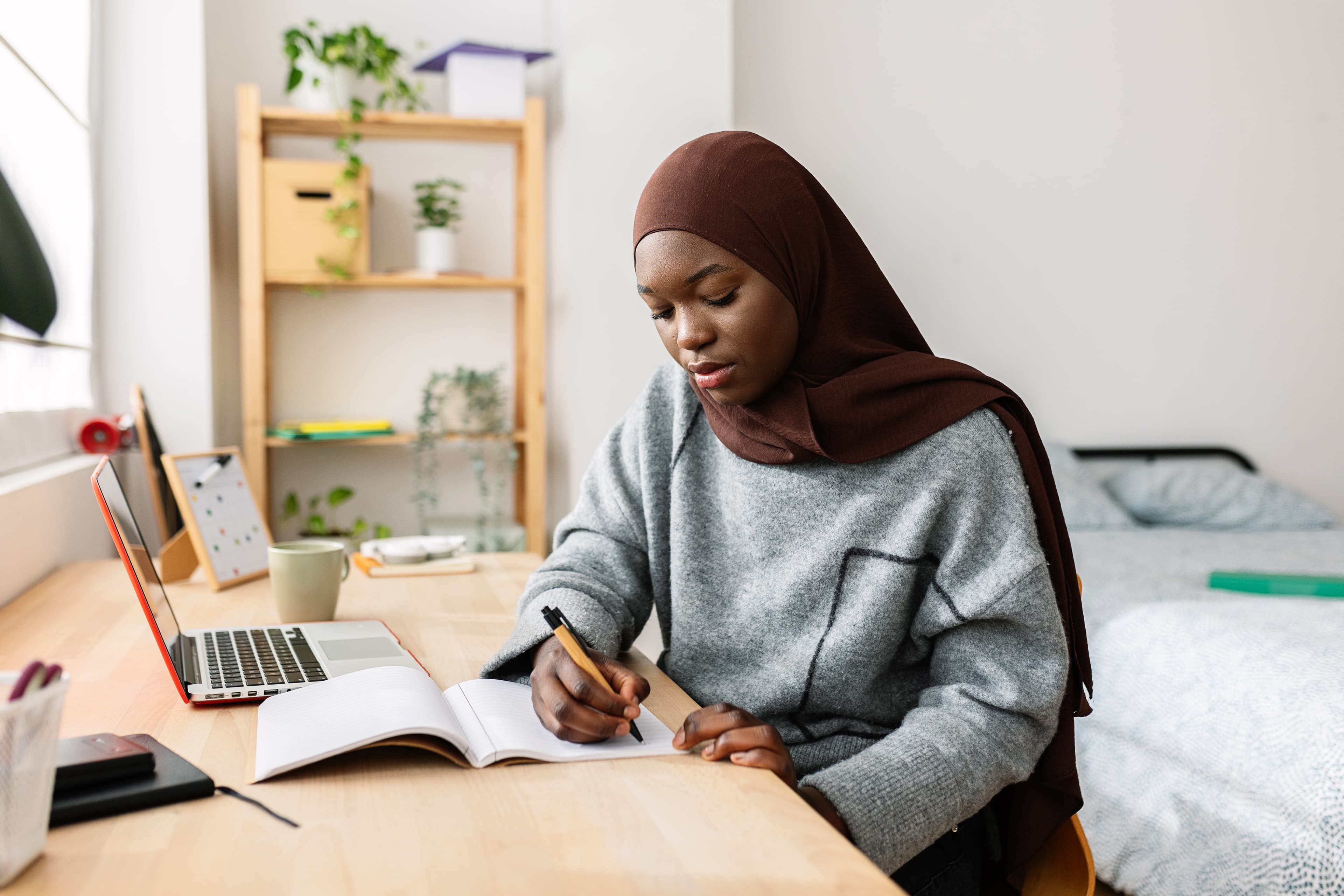 A law student sitting alone at a desk with notebooks, looking pensive but determined